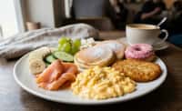 Composed Breakfast Plate with Smoked Salmon, Soft Eggs, Mini Pancakes, and Pink-Glazed Donut